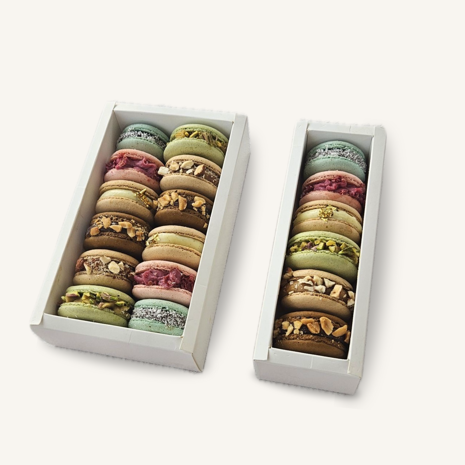Assortiment de macarons artisanaux dans deux box blanches, avec différents parfums et garnitures, présentation premium pour coffrets de macarons